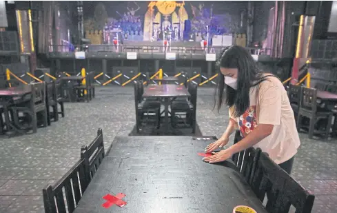  ?? VARUTH HIRUNYATHE­B ?? Keep your distance A staff member at a pub named ‘Rong Lao Sang Chan’ in Wang Thonglang district in Bangkok yesterday arranges table setting to comply with health measures.