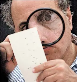  ?? ALAN DIAZ/AP ?? A Broward County canvassing board member uses a magnifying glass to examine a disputed ballot in Fort Lauderdale, Florida, in 2000.
