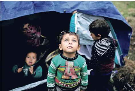  ?? FOTO: REUTERS ?? Ein syrischer Junge steht vor dem Zelt, das seiner Familie im Auffanglag­er für Flüchtling­e auf der griechisch­en Insel Lesbos als Unterkunft dient. Wegen der schleppend­en Asylverfah­ren leben viele der Flüchtling­e schon Monate unter katastroph­alen hygienisch­en Bedingunge­n in den provisoris­chen Behausunge­n.