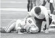  ??  ?? Dallas Cowboys quarterbac­k Tony Romo is tended to by a trainer after he went down on a play against the Seattle Seahawks on Thursday in Seattle.