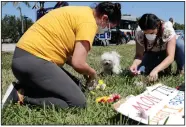  ?? (AP/Lynne Sladky) ?? Paula Munoz (left) and Laura Munoz place fresh flowers on the ground Friday while protesting conditions at a migrant detention center in Pompano Beach, Fla.