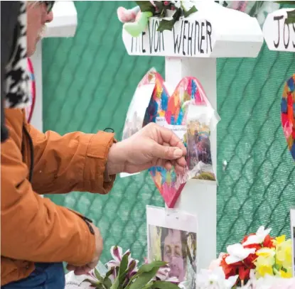  ?? ASHLEE REZIN/SUN-TIMES ?? Five white crosses were adorned by the attendees of Sunday’s vigil with photograph­s, mementoes such as beanie babies, flowers and candles.