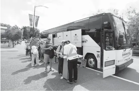  ?? DARREN STONE, TIMES COLONIST ?? Travellers wait to board a bus outside the Capital City Station, part of Crystal Garden.