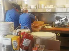  ?? BILL RETTEW JR. – DIGITAL FIRST MEDIA ?? Workers huddle over the grill at a Waffle House.