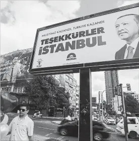  ?? EMRAH GUREL THE ASSOCIATED PRESS ?? A day after the elections, people walk past a billboard with the image of Turkey's president Recep Tayyip Erdogan in Istanbul.
