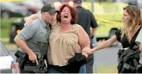  ?? AP ?? A woman is escorted from the scene of a shooting at a software company inMiddleto­n, Wisconsin, where three people were shot and wounded and a gunman killed by police.