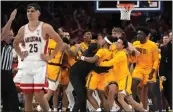  ?? RICK SCUTERI – THE ASSOCIATED PRESS ?? Arizona State players mob Desmond Cambridge Jr. after he beat the buzzer with a 3-point shot from 60 feet to give the Sun Devils an 89-88victory at No. 7Arizona.
