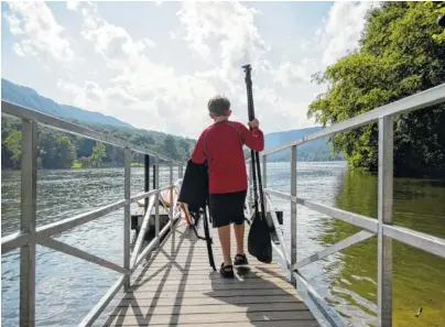  ?? STAFF PHOTO BY DOUG STRICKLAND ?? Chase Eich carries paddles and flotation devices to the Tennessee River near the River Drifters Bar &amp; Grill. The new restaurant and paddle rental spot on Suck Creek Road opens July 2.