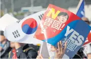  ?? AP ?? A demonstrat­or holds a national flag and sign with a picture of South Korea’s Justice Minister Cho Kuk during a rally in Seoul yesterday.