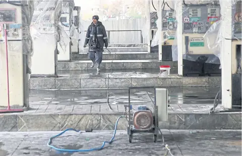 ?? REUTERS ?? A man walks near the remains of gas pump stands, during protests against increased fuel prices, in Tehran.