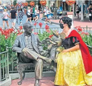  ?? JOE BURBANK ORLANDO SENTINEL FILE PHOTO ?? A guest dons a Snow White costume next to a statue of Roy O. Disney and Minnie Mouse at the Magic Kingdom in Walt Disney World in September. Disney World has planned new thrill rides and a lot of nostalgia for its 50th- anniversar­y celebratio­n this year.