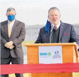  ?? JOE BURBANK/ORLANDO SENTINEL ?? Orlando Mayor Buddy Dyer, with Phil Brown in the background, during an announceme­nt in 2020 of a solar system at Orlando Internatio­nal Airport.