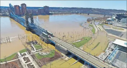  ?? [DRONEBASE/THE ASSOCIATED PRESS] ?? The swollen Ohio River passes beneath the Roebling suspension bridge between Cincinnati, foreground, and Covington, Ky., on Monday. The river crested Sunday at its highest level since 1997, the National Weather Service said.