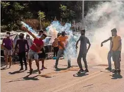  ?? Foto: AFP ?? Migranten liefern sich bei Mytilene auf Lesbos eine Auseinande­rsetzung mit der Polizei, die Tränengas einsetzt.