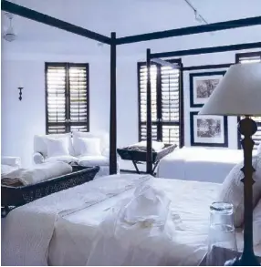  ??  ?? The contrast created by South African designer Stephen Falcke between the dark mahogany furniture and crisp white bed linen in this bedroom is softened by the diffusal light from the louvered windows.