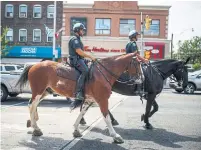  ?? MARK BLINCH/THE CANADIAN PRESS ?? Mounted police patrol Danforth Ave.