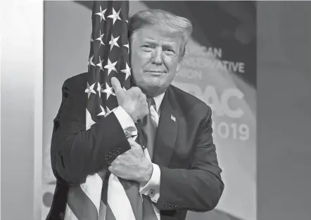  ?? CAROLYN KASTER/AP ?? Then-president Donald Trump hugs the American flag as he arrives to speak at the Conservati­ve Political Action Conference on March 2, 2019, in Oxon Hill, Md. Trump appeared at the conference Sunday.