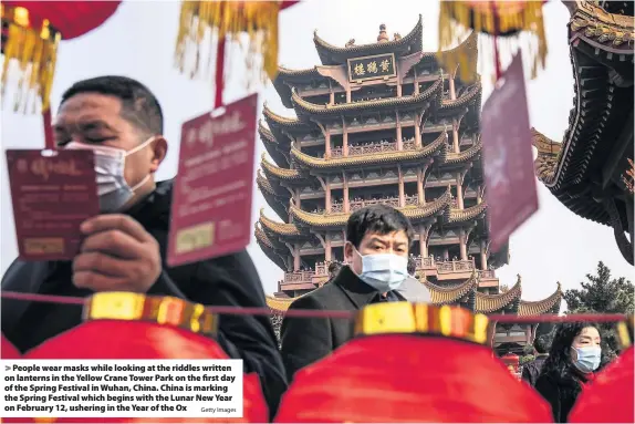  ?? Getty Images ?? People wear masks while looking at the riddles written on lanterns in the Yellow Crane Tower Park on the first day of the Spring Festival in Wuhan, China. China is marking the Spring Festival which begins with the Lunar New Year on February 12, ushering in the Year of the Ox