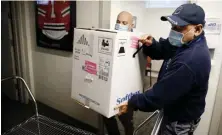  ?? POOL PHOTOs ?? IT’S HERE: Victor Ruiz, left, and and Richard Guarino, both with BMC Supply Chain Operations, place the hospital’s first shipment of the Pfizer-BioNTech COVID19 vaccine on a cart.