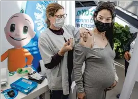  ?? Jack Guez AFP/Getty Images ?? A HEALTHCARE WORKER administer­s a dose of the Pfizer-BioNTech COVID-19 vaccine to a pregnant woman at Clalit Health Services in Tel Aviv.