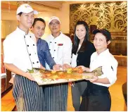  ??  ?? CEF OMAR (tengah), bersama cef-cef lain dan kakitangan Melinau Terrace dan ParkCity Everly Hotel menunjukka­n ikan salmon panggang dari New Zealand.