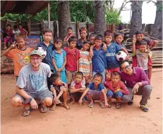  ?? FOTO: MATHIEU ?? Links zu sehen ist der Erzieher Michael Mathieu, rechts Kunnareth Por, der Schulleite­r. Dazwischen posieren die Kinder des kambodscha­nischen Dorfes, mit denen Mathieu ein Fußballpro­jekt macht.