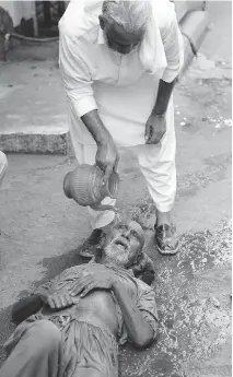  ?? RIZWAN TABASSUM/AFP/GETTY IMAGES FILES ?? A Pakistani resident helps a heatstroke victim at a market during a heat wave in Karachi in June.