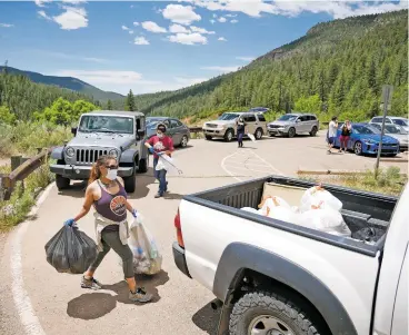  ??  ?? ABOVE: Candice Sando throws bags of trash into the back of a U.S. Forest Service truck Wednesday at Spence Hot Springs while helping clean up day-use areas in Santa Fe National Forest’s Jemez Ranger District. Sando and other residents of Jemez Pueblo volunteere­d to pick up garbage around the forest after visitors left trash throughout the area over Memorial Day weekend.