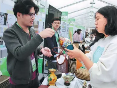  ?? XINHUA ?? Two college students exchange ideas about new products at a fair to boost innovation and entreprene­urship in Shanghai.