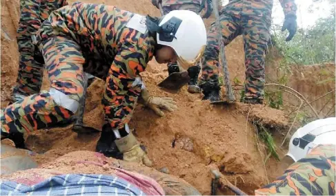  ?? ?? Worksite death: Firemen searching for the backhoe driver who was buried in the landslide in Kampung raja, Cameron Highlands. — Photo from Cameron Highlands fire station Facebook page