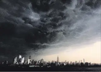  ?? DENIS PAQUIN THE ASSOCIATED PRESS ?? Storm clouds gather Tuesday over New York seen from the Hudson River. A line of strong storms pushed across New York City .