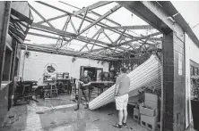  ?? John Blackie / Associated Press ?? Employees assess the damage to the Emerald Republic Brewing building Saturday after a storm hit Pensacola, Fla.