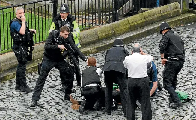  ?? PHOTO: GETTY IMAGES ?? A police officer points a gun at a man lying on the ground after the London attack. A man was shot by police after people on Westminste­r Bridge were run down by a car and an officer at the Houses of Parliament was fatally stabbed.