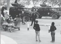  ?? AP PHOTO ?? Residents watch a convoy of security personnel and armoured vehicles in a show of force through central Kashgar in western China’s Xinjiang region in 2017. Since 2016, Chinese authoritie­s in the heavily Muslim region of Xinjiang have ensnared tens,...