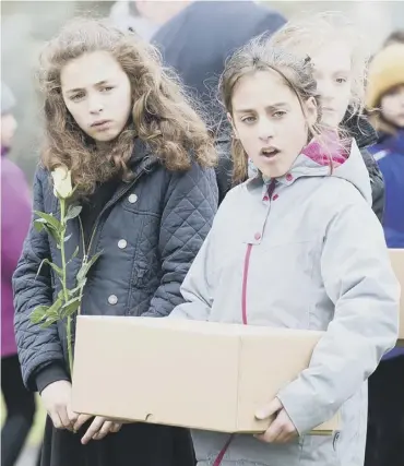  ??  ?? Pupils from St Mary’s primary school carry plague victims’ remains to be buried. Top, roses were laid in the graves. Above, Rev Iain May and councillor Donald Wilson