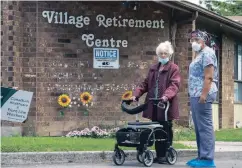  ?? FRANK GUNN THE CANADIAN PRESS ?? A resident and a worker watch as 150 nursing union members show support at Orchard Villa care home in Pickering on Monday. Long-term-care homes have borne the brunt of the pandemic, with more than 4,000 residents dying in Ontario and Quebec alone.