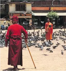  ?? PHOTOS: ANNIE GROER/THE WASHINGTON POST ?? Near the Boudhanath Stupa in Kathmandu, a monk stands still among the pigeons, begging bowl in hand, while another makes his way through the square.