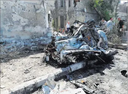  ??  ?? People gather at the scene of an explosion Sunday along the road to the airport in southeast Damascus, Syria. The Associated Press