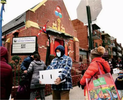  ??  ?? People receive free food from the United Sherpa Associatio­n’s weekly food pantry in the Queens borough of New York.