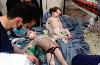  ?? AP ?? This image, made from video released by the Syrian Civil Defense White Helmets, shows medical workers treating toddlers following an alleged poison gas attack Sunday in the opposition-held town of Douma, near Damascus, Syria.