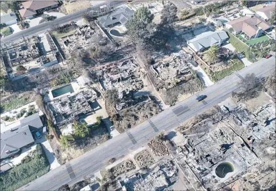  ?? Brian van der Brug Los Angeles Times ?? EMMA JACOBSON, top left, gets a hug from a neighbor after her home was destroyed in the Thomas fire in Ventura. A Santa Barbara County firefighte­r, top right, extinguish­es hot spots while traversing steep terrain near Montecito. A drone’s-eye view,...