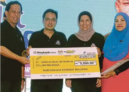  ?? PIC BY HAIRUL ANUAR ?? Domestic Trade and Consumeris­m Ministry secretary-general Datuk Seri Jamil Salleh (left) presenting a mock cheque to SMT Johor Baru’s principal Halimah Kanan in Johor Baru yesterday. With them are the ministry’s deputy minister, Chong Chieng Jen...