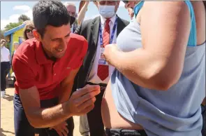 ?? The Associated Press ?? Novak Djokovic autographs the stomach of fan Vanessa Kezerle, who is pregnant, following a photoshoot Monday at Brighton Beach after winning the Australian Open in Melbourne a day earlier.
