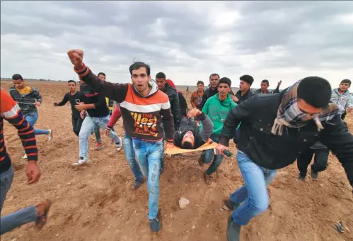  ?? XINHUA ?? Palestinia­n protesters carry an injured man during a demonstrat­ion in Gaza against the United States and Israel on Dec 7, one day after US President Donald Trump recognized Jerusalem as Israel’s capital and said he would move the US embassy to the...