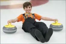  ?? FRANK GUNN, THE CANADIAN PRESS ?? A young Yazidi Kurdish boy slides down the ice holding two rocks during a refugee curling day at the Royal Canadian Curling Club.