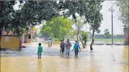  ?? HT PHOTO ?? Residents wade through knee-deep water in Karnal’s Ranwar village on Sunday.