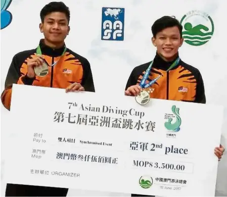  ??  ?? Stars of the future: Hanis Nazirul Jaya Surya (left) and Jellson Jabillin displaying their silver medals and mock cheque after finishing second in the men’s 10m platform synchro at the Asian Diving Cup in Macau.