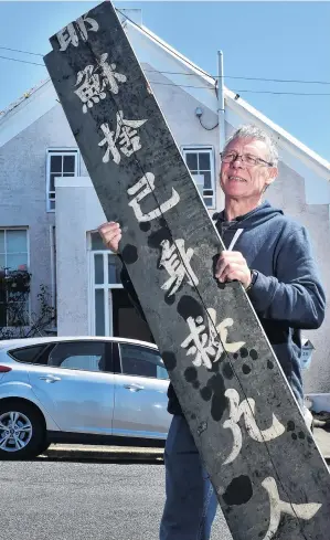  ?? PHOTO: PETER MCINTOSH ?? God is love . . . Property owner Mark Thom holds a board understood to be more than 100 years old, found at a former Chinese Presbyteri­an church.