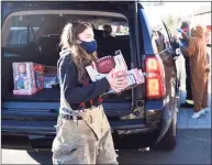  ?? Tyler Sizemore / Hearst Connecticu­t Media ?? Darien junior Maya Patrosz collects donations at the Christmas car parade at Darien High School in Darien on Dec. 6. Darien’s three fire department­s held a holiday drive-thru for cars featuring fire trucks and an appearance by Santa Claus. Donations for Toys for Tots and Person to Person were also collected at the event.