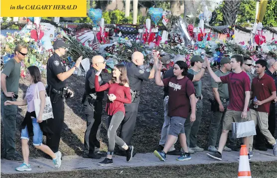  ?? MIKE STOCKER / SOUTH FLORIDA SUN-SENTINEL VIA AP ?? Officers greet students at Marjory Stoneman Douglas High School in Parkland, Fla., as they head back to class on Wednesday for the first time since the Feb. 14 mass shooting.